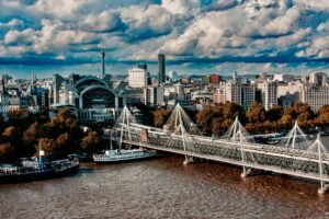 Stunning aerial view of Hungerford Bridge and London skyline with dramatic clouds.