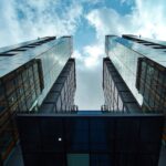 Low-angle view of sleek, modern skyscrapers with glass facades under a blue sky.